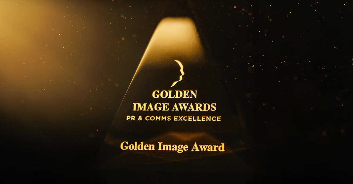 A close-up photograph of the Golden Image Awards pyramid trophy with black background and shining golden spotlight.