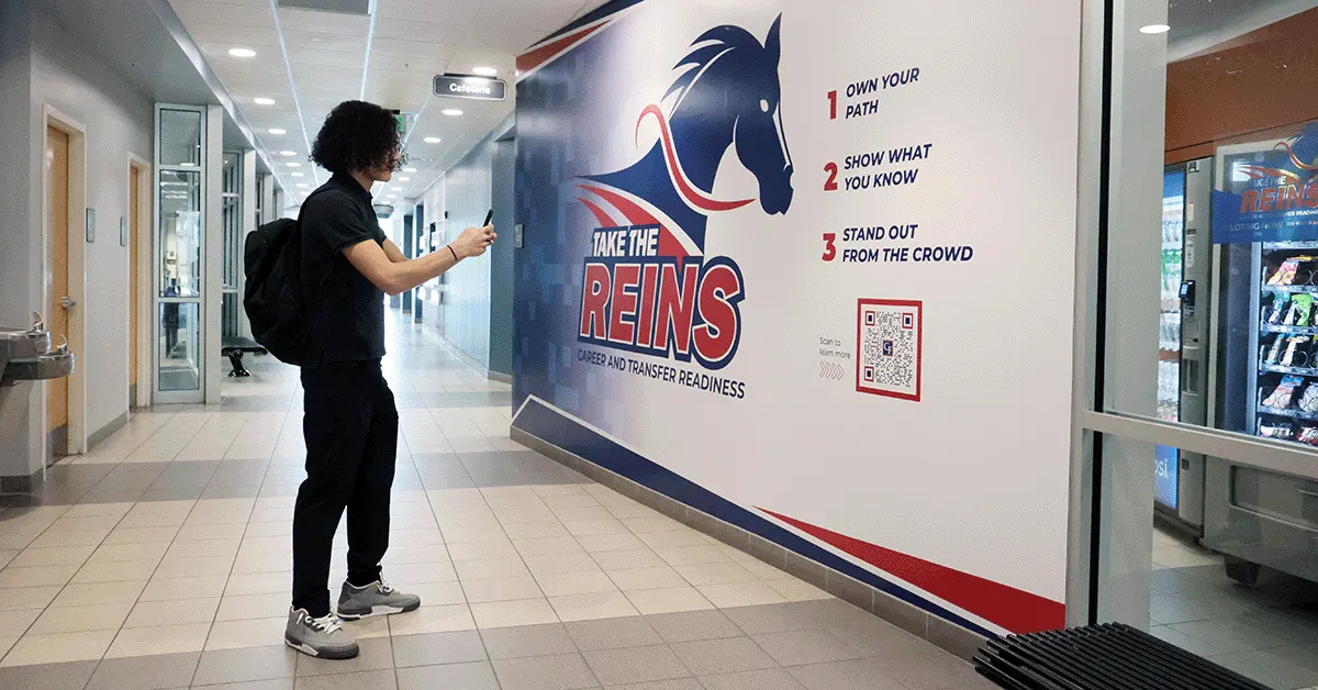 A student at College of Central Florida stands down a hallway with the walls branded for the Take the Reins campaign.